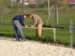 Manuel Bühler und Christian Bittner überprüfen die Abstände der Hülsen anhand einer der Latten, die über die Pfosten kommen sollen....